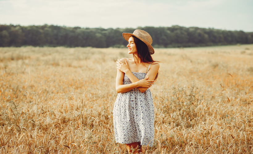 Mujer en el campo, morena con un vestido estanpado y un sombrero